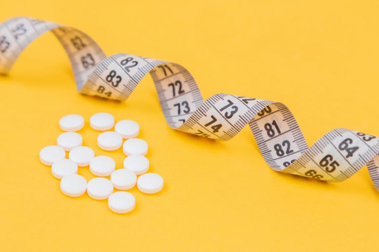 Gewichtszunahme durch Antibiotika? Tabletten und Maßband