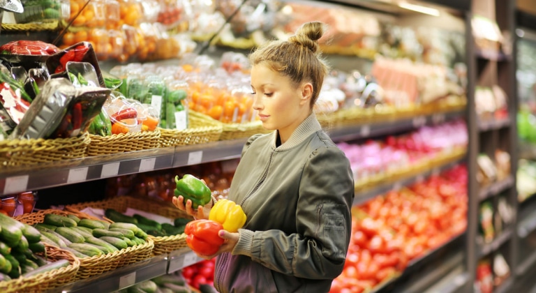 Die richtige Ernährung bei chronisch entzündlichen Darmerkrankungen - Frau steht mit Paprika in der Gemüseabteilung